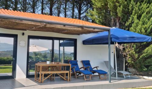 a patio with a table and chairs and a blue umbrella at Lugar Nas Estrelas Starlight Outdoor Fireplace in Peso