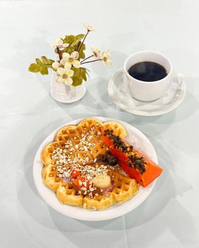 a plate of waffles on a table with a cup of coffee at Harbor Inn Jaraguá in Jaraguá do Sul