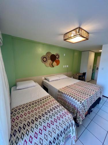 two beds in a room with green walls at FLAT EM BARREIRINHAS - Gran Solare Lencois in Barreirinhas