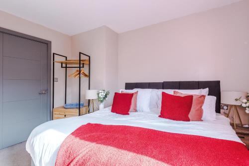 a bedroom with a large bed with red pillows at Modern 2BR near Wigan Town Centre in Wigan