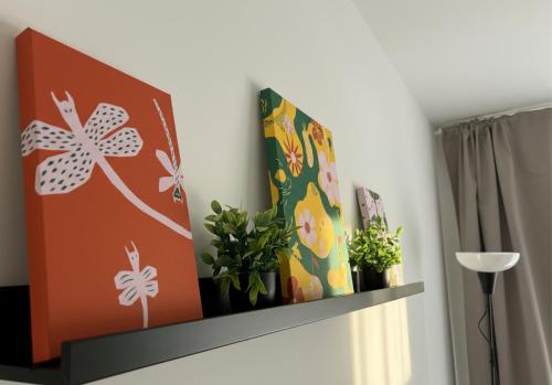 a shelf with plants and paintings on a wall at Spacious Apartment with Balcony - nearby Schlosspark - APOLONIAliving in Karlsruhe