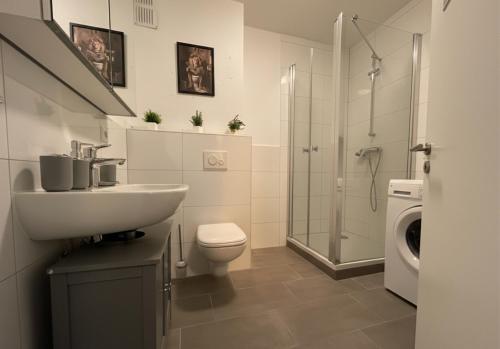 a bathroom with a sink and a toilet and a shower at Spacious Apartment with Balcony - nearby Schlosspark - APOLONIAliving in Karlsruhe
