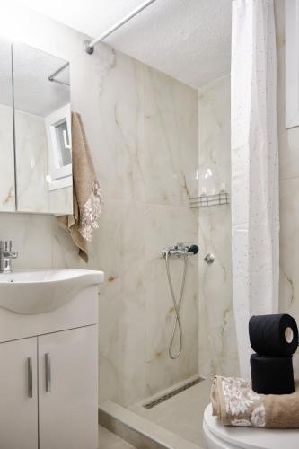 a white bathroom with a shower and a sink at Doreta's House Elia in Veria