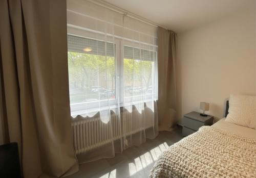 a bedroom with a bed and a window with curtains at Spacious Apartment with Balcony - nearby Schlosspark - APOLONIAliving in Karlsruhe