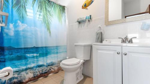 a bathroom with a white toilet and a beach shower curtain at Surf Beach Apt 201- One block from the beach in Rincon