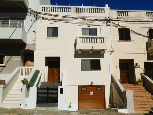a white house with brown doors and stairs at Bright & Spacious Private Room, Bathroom & Terrace in Swieqi, Prime Location! in Is-Swieqi