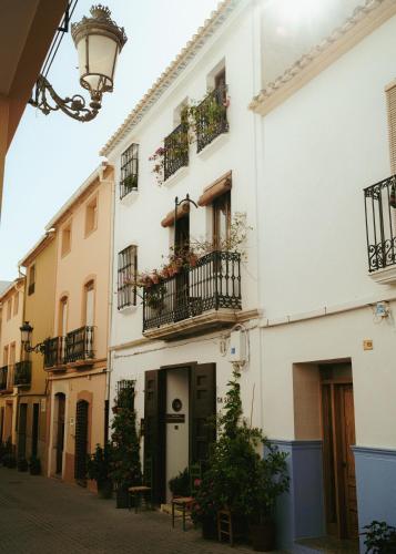 a white building with balconies and potted plants at Ca Sana Teulada Moraira, Grupo Terra de Mar, alojamientos con encanto in Moraira