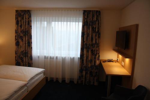 a bedroom with a bed and a window with a television at Hotel Bahnhof Jestetten in Jestetten