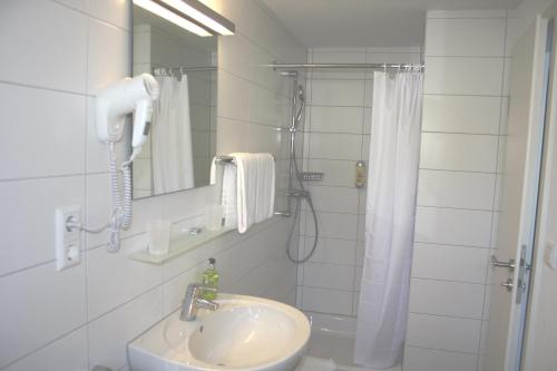 a white bathroom with a shower and a sink at Hotel Bahnhof Jestetten in Jestetten