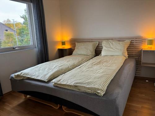 a bed in a bedroom with two lamps and a window at HB HolidayHomes - The White Pearl in Tromsø