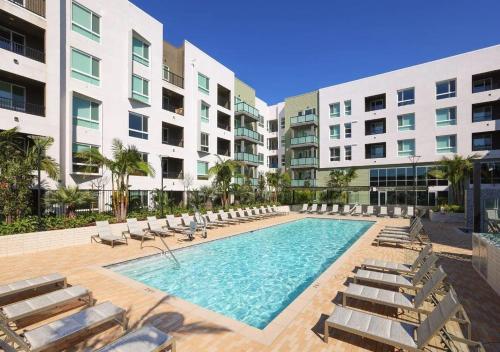 a swimming pool with lounge chairs and a building at Sunlit Retreat 10 Min from Disneyland With Pool & GYM in Tustin