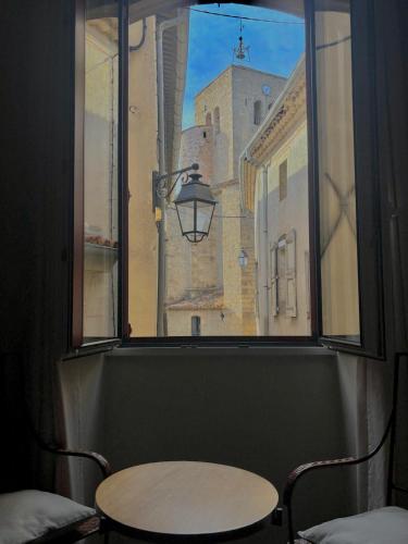 a window with a table and a street view at Chambres d'Hôtes Le Mimosa in Saint-Saturnin-de-Lucian