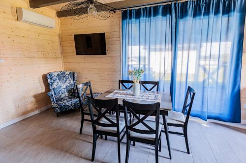 a dining room with a table and chairs and a tv at Podlaskie Chatki Ciszą Malowane - Domek nr 2 in Krynki