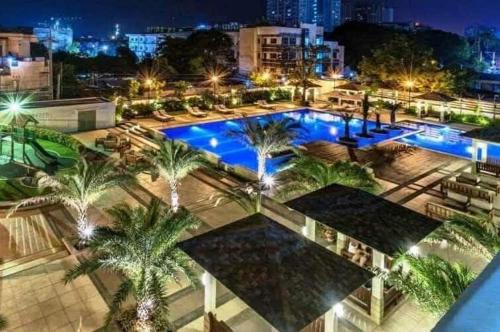 a large pool with palm trees in a city at night at 1BR LaVerti Cloud Nine Suite Family Affordable Staycation in Manila