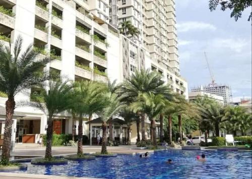 a large swimming pool with palm trees in front of a building at 1BR LaVerti Cloud Nine Suite Family Affordable Staycation in Manila