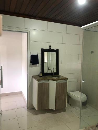 a bathroom with a sink and a toilet and a mirror at Tranquilidade e Ótima localização in São José