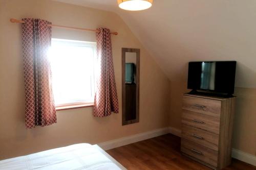 a bedroom with a bed and a tv and a window at Loophead SelfCatering Cottage SensoryAccessible in Kilrush