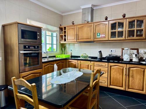 a kitchen with wooden cabinets and a table with chairs at Vista Ventura in Ponta Delgada