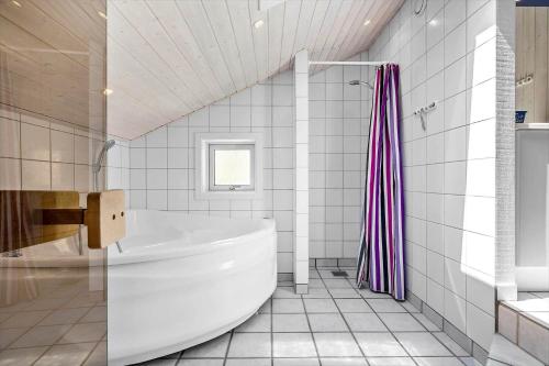 Un baño blanco con bañera y ducha. en 2669 Nexø - Møllestien 11, en Vester Sømarken