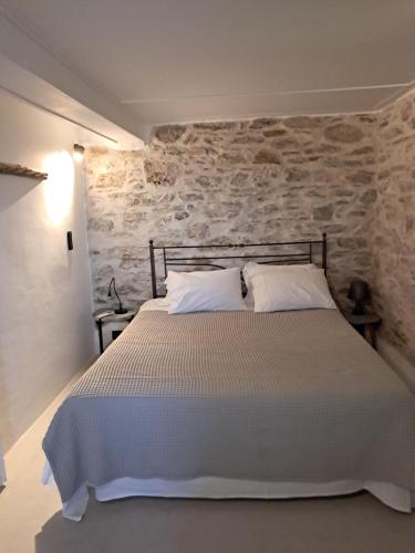 a bedroom with a bed with a stone wall at Akros-cottage on mountain- ground floor in Stavrinídes