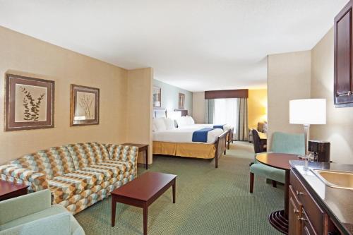 a large hotel room with a bed and a couch at Holiday Inn Express and Suites Meriden by IHG in Meriden