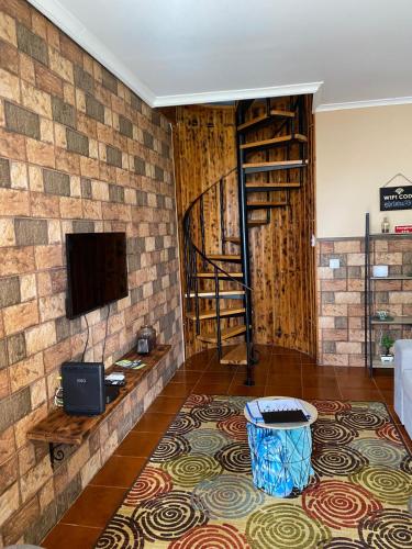 a living room with a tv on a brick wall at Casa da Vista- Eirinha in Furnas