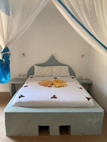 a bed in a room with a white bedvisor at Stonefish Inn Jambiani in Jambiani