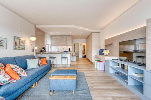 a living room with a blue couch and a kitchen at Meerzeit Norderney in Norderney