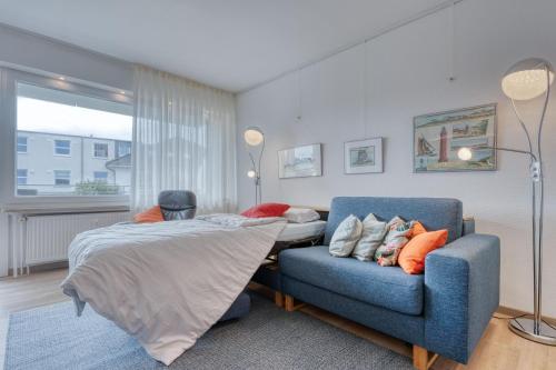 a bedroom with a bed and a blue chair at Meerzeit Norderney in Norderney