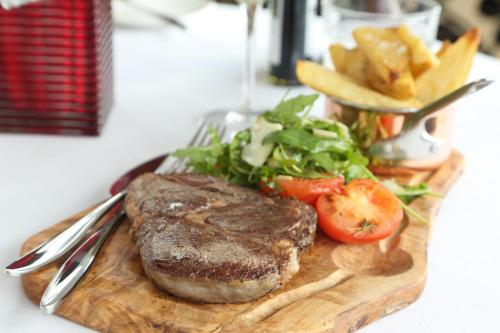 a steak on a cutting board with a salad and fries at Holiday Inn Manchester-Mediacityuk by IHG in Manchester