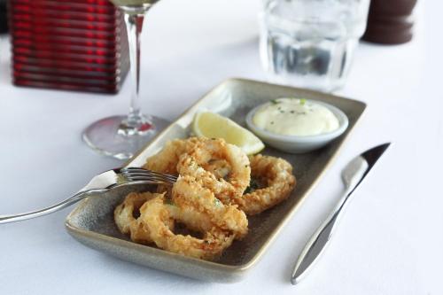 a plate of calamari with a fork and a lemon at Holiday Inn Manchester-Mediacityuk by IHG in Manchester
