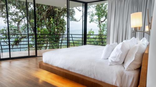 a bedroom with a bed and large glass windows at Saloya Mindo Life Landscape Hotel in Chigüipe