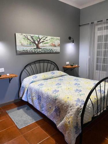 a bedroom with a bed and a painting on the wall at Casa da Vista- Eirinha in Furnas