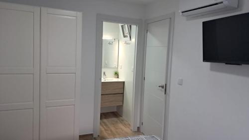 a bathroom with a sink and a tv and a mirror at CasaCorvera in Corvera