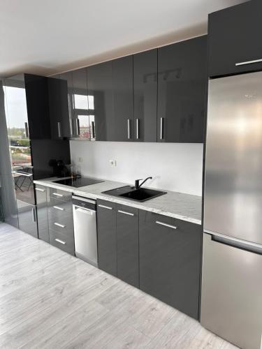 a kitchen with black cabinets and a stainless steel refrigerator at Luxury Lavender Gorgeous Terrace Free UNDG Parking in Timişoara