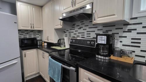 a kitchen with white cabinets and black appliances at Cozy 2 Bedroom Suite, 5 mins from Thermea Spa in Whitby