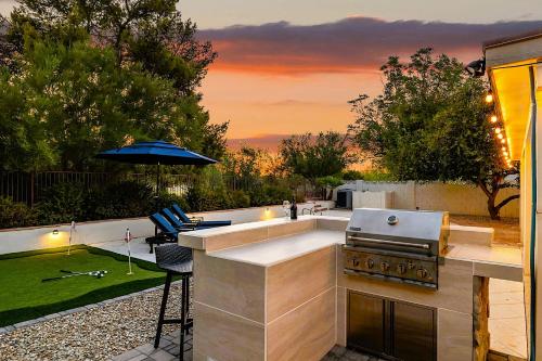 an outdoor kitchen with a grill and an umbrella at Chaparral Dog Park & Lake, Heated Pool, Pets Allowed in Scottsdale