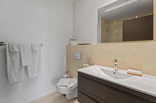 a bathroom with a sink and a toilet and a mirror at Eagle Beach - Luxury Beachscape 2BR condo - LV302 in Palm-Eagle Beach
