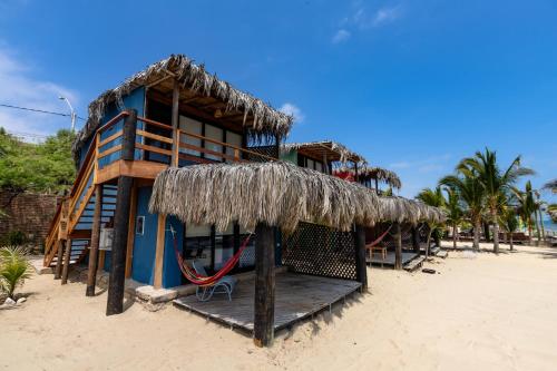 a building on the beach with a straw roof at Hoja de Palma Bungalows in Canoas De Punta Sal