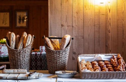 two baskets of bread and a basket of pastries on a table at Alpes Hôtel du Pralong in Courchevel