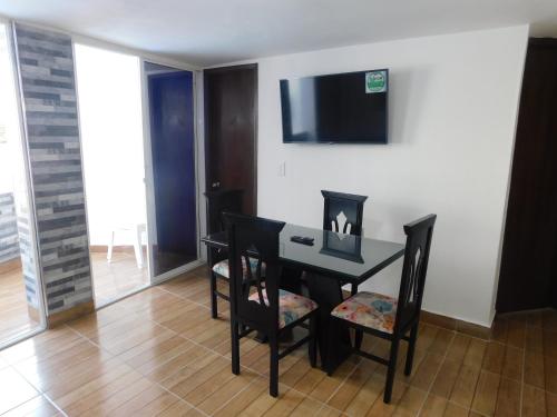 a dining room with a table and chairs and a television at El Velero Apartamentos By DANP in Santa Marta