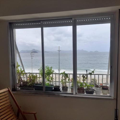 une fenêtre avec des plantes et une vue sur l'océan dans l'établissement Flat Mar e Sol, à Rio de Janeiro
