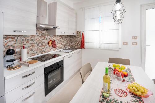 a white kitchen with a table with fruit on it at Casa Amelia in Letojanni
