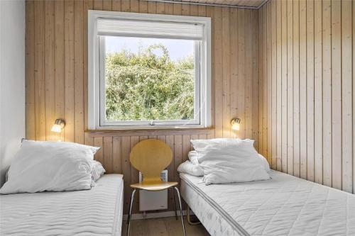 two beds in a room with a window and a chair at 6682 Allinge - Brunekulvej 2 E in Allinge