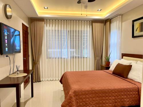 ein Hotelzimmer mit einem Bett und einem Flachbildfernseher in der Unterkunft Humble Cocoon1-2BR Unit House Near Inflatable Island & Subic Bay Yacht in Subic