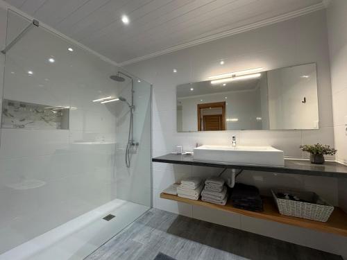 a white bathroom with a sink and a shower at A Mercearia in Água de Pau