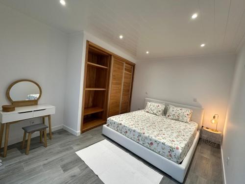 a white bedroom with a bed and a desk at A Mercearia in Água de Pau