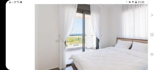 Un dormitorio con una cama y una ventana grande. en אכזיב על הים, en Nahariyya