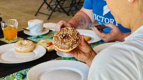a woman is holding a donut on a table at Le Saline Rooms Marzamemi in Marzamemi
