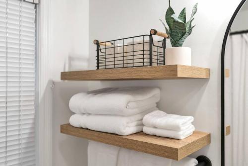 a stack of towels on a wooden shelf in a bathroom at Cozy modern duplex 5 min to downtown Spartanburg in Spartanburg